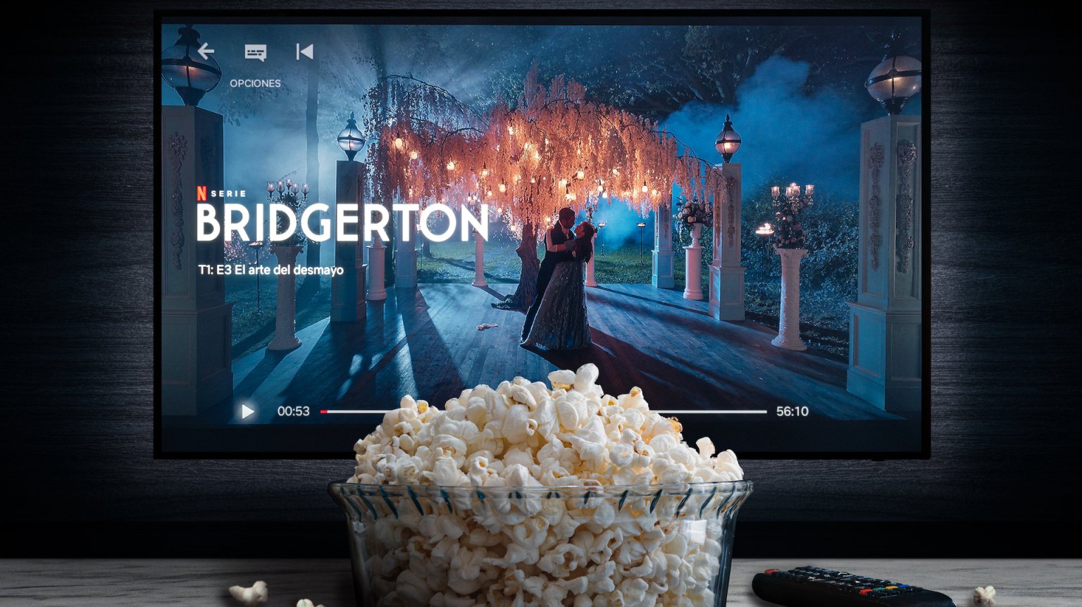 A TV screen is paused on the Netflix show "Bridgerton" with a bowl of popcorn sitting in front of it.