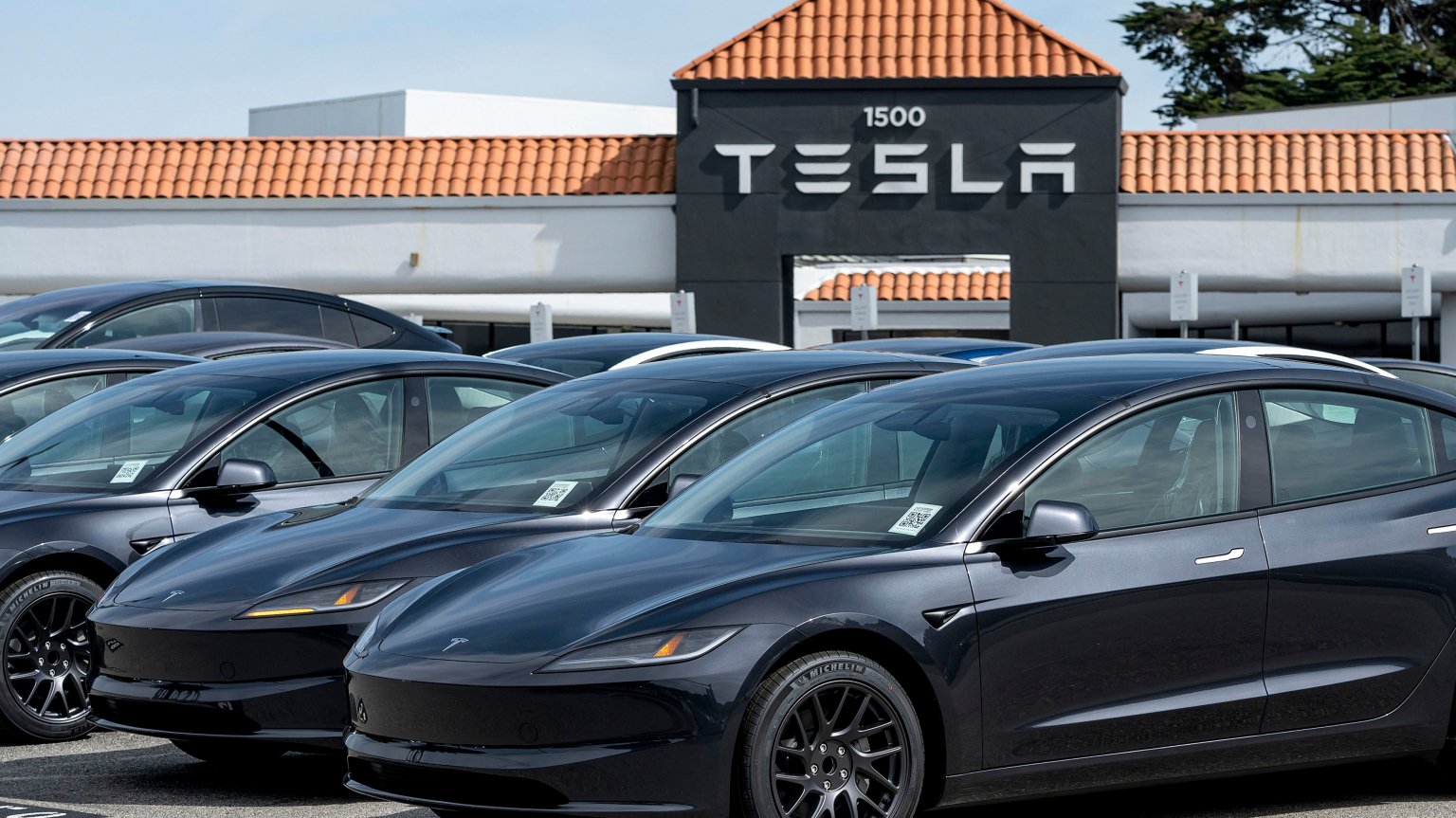 teslas in a parking lot with a tesla sign in the background