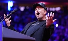 Elon Musk screaming at a Trump rally wearing a 'dark MAGA' hat