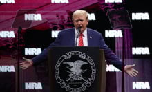 Trump stands in front of a podium on stage at the National Rifle Association (NRA) annual meeting. 