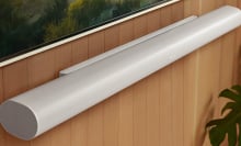 sonos arc ultra soundbar mounted on wood-paneled wall under tv screen