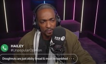 A man sits in a radio booth frowning.