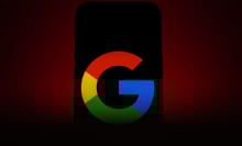 A phone in ominous red lighting displaying a Google logo.