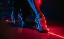 A woman's legs, wearing in high heels shoes under red illumination