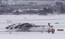 Airport workers survey the site of a Delta Air Lines plane crash that injured at least 18 passengers at Toronto Pearson International Airport on February 18, 2025 in Toronto, Canada. The jet, coming in from Minneapolis, attempted to land amid strong winds and snow, leading to it crashing and landing upside down on the tarmac the day before.