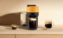 a mango yellow nespresso vertuo pop+ coffee maker sits on a countertop with several coffee drinks