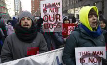 A group of federal workers protesting on the streets of New York. They hold signs with Elon Musk's face that read "This man is not our boss."