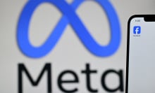  Meta logo is displayed on a laptop screen next to the Facebook app displayed on a phone screen, in a residential property in Guildford, south of London.