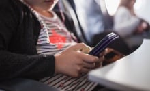 A young girl looks at her smartphone.