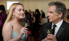 A woman stands on the red carpet interviewing a man in a suit.