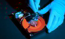 close-up of gloved hands tinkering with hard drive