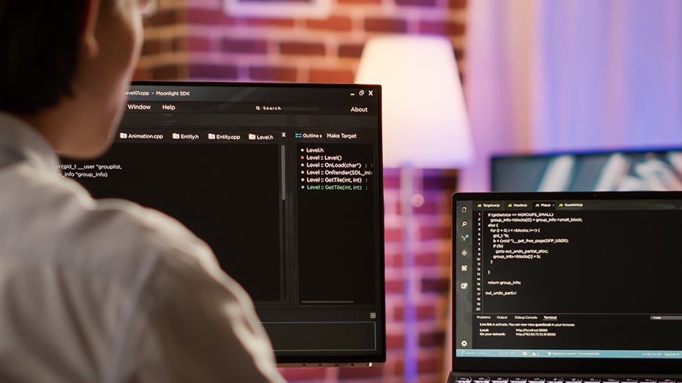 man writing code on computer monitors