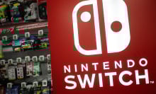 A red Nintendo Switch sign in front of a display of Switch games.