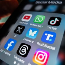 An iPhone app folder with several icons for popular social media apps, including Bluesky, X, and Truth Social.