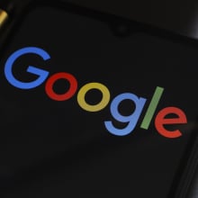 A phone displays the rainbow colored Google logo.