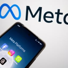 An image of Meta's logo with a phone displaying different Meta company apps. 