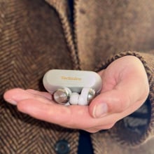 close-up of man holding panasonic technics az100 wireless earbuds with silver charging case