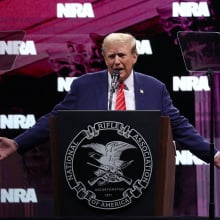 Trump stands in front of a podium on stage at the National Rifle Association (NRA) annual meeting. 