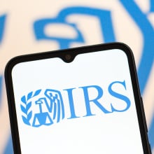 A phone screen displaying a light blue IRS logo. 