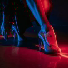 A woman's legs, wearing in high heels shoes under red illumination