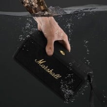 a person's left hand submerges the marshall middleton speaker into water
