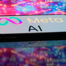 A phone displays a Meta AI logo in front of a glowing, multi-colored background.