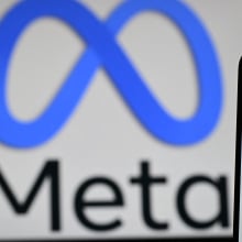  Meta logo is displayed on a laptop screen next to the Facebook app displayed on a phone screen, in a residential property in Guildford, south of London.