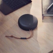 a black bang & olufsen beosound a1 speaker on a wood desk