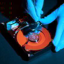 close-up of gloved hands tinkering with hard drive