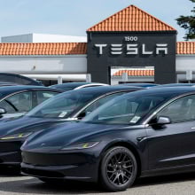 teslas in a parking lot with a tesla sign in the background