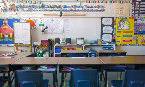A kindergarten classroom with a whiteboard and decorated walls.
