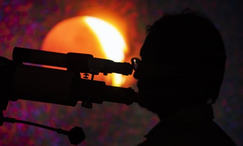 A man using a telescope at Guwahati Planetarium during a total lunar eclipse on Nov. 8, 2022 in Guwahati, India.