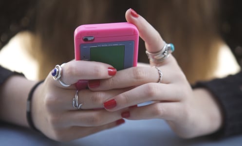 teenage girl with red nail polish holding iphone with pink case