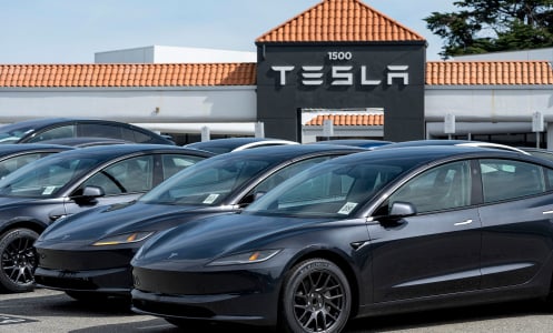 teslas in a parking lot with a tesla sign in the background
