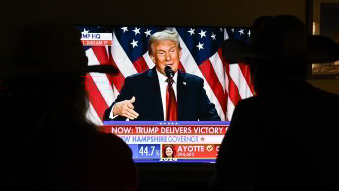 A couple watch President Donald Trump's victory speech from a TV screen.