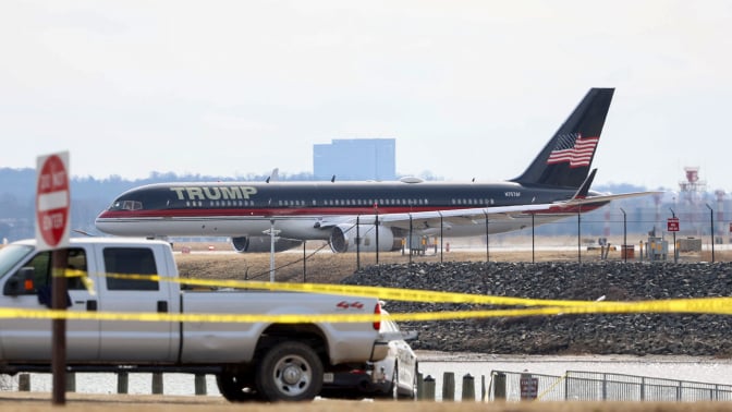 Trump's personal plane parked on the tarmac at Reagan National airport. Caution tape is strung across a street in front of it.