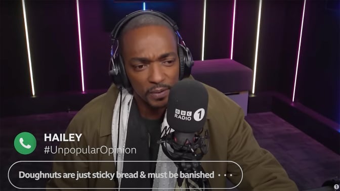A man sits in a radio booth frowning.