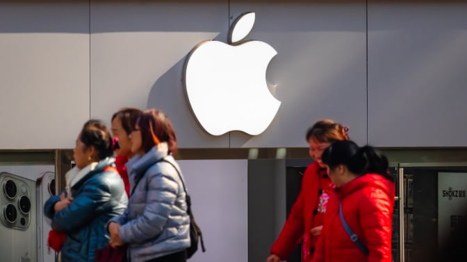 People walk past an Apple store with its iconic logo displayed on the storefront