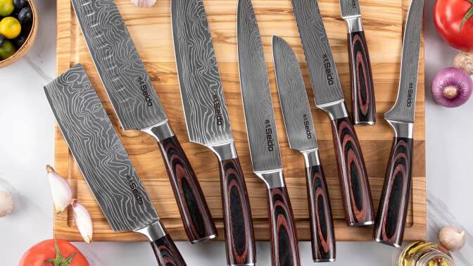 eight Seido Japanese chef knives on countertop with vegetables