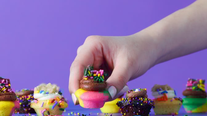 Hand grabbing Baked by Melissa cupcakes