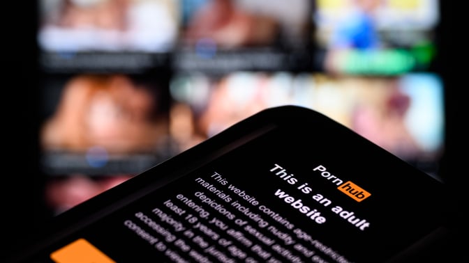 the age-restriction warning screen of the website Pornhub is displayed on a digital screen