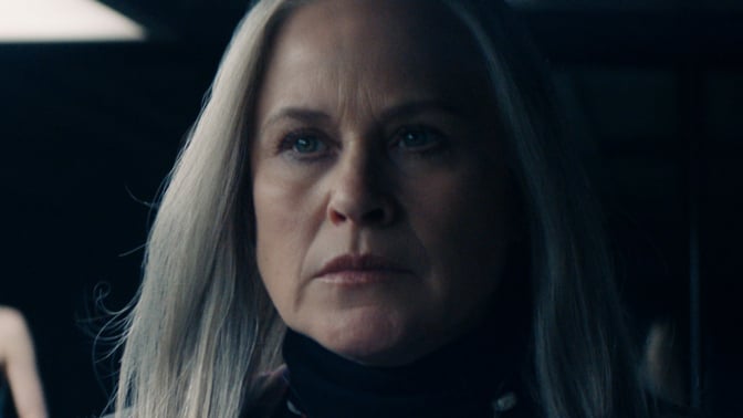 A close-up of a woman looking serious in a dark room.