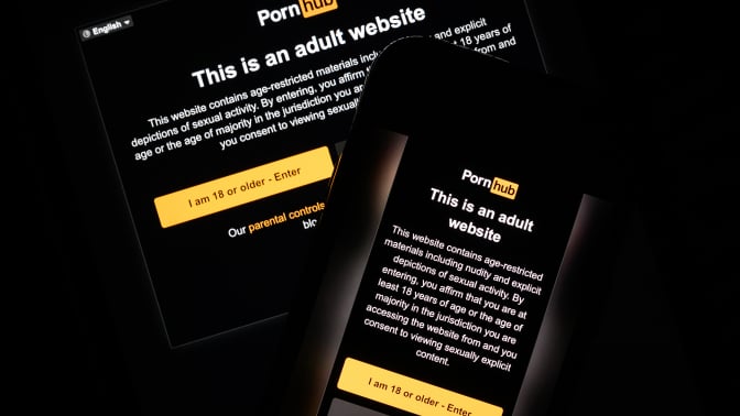 In this photo illustration, the age-restriction warning screen of the website PornHub is displayed on two digital screens