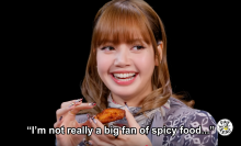 Lisa holding a chicken wing on "Hot Ones."
