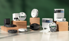 Assorted black and white Roomba robot vacuums arranged with green backdrop