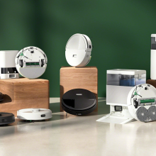 Assorted black and white Roomba robot vacuums arranged with green backdrop