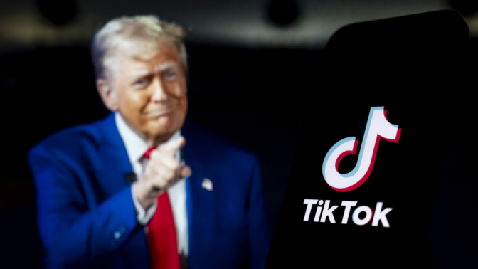 The logo of TikTok is displayed on mobile phone screen in front of a computer screen displaying United States President Donald Trump.