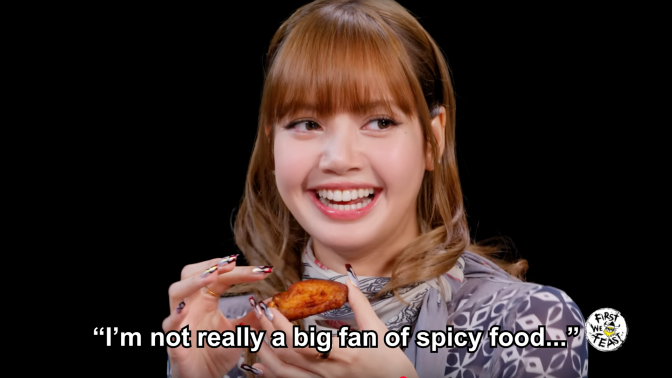 Lisa holding a chicken wing on "Hot Ones."