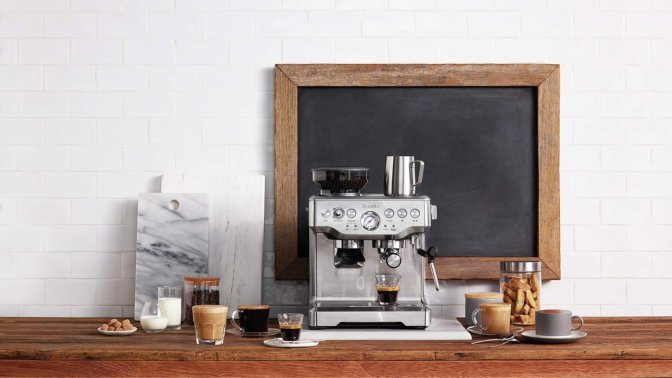 A Breville Espresso Maker on a countertop surrounded by beverages